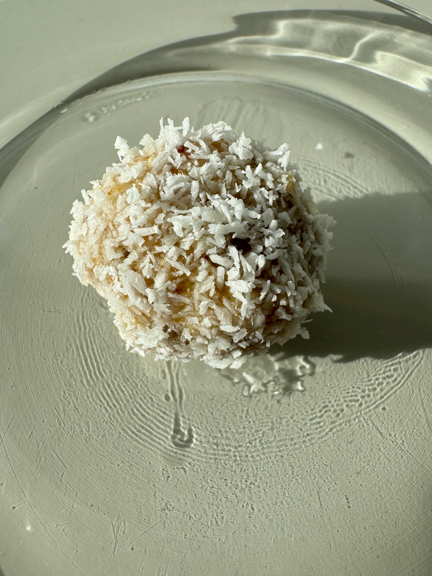 A plate of round bliss ball made of oats, almonds, dates, and coconut, sprinkled with cinnamon and coconut flakes.