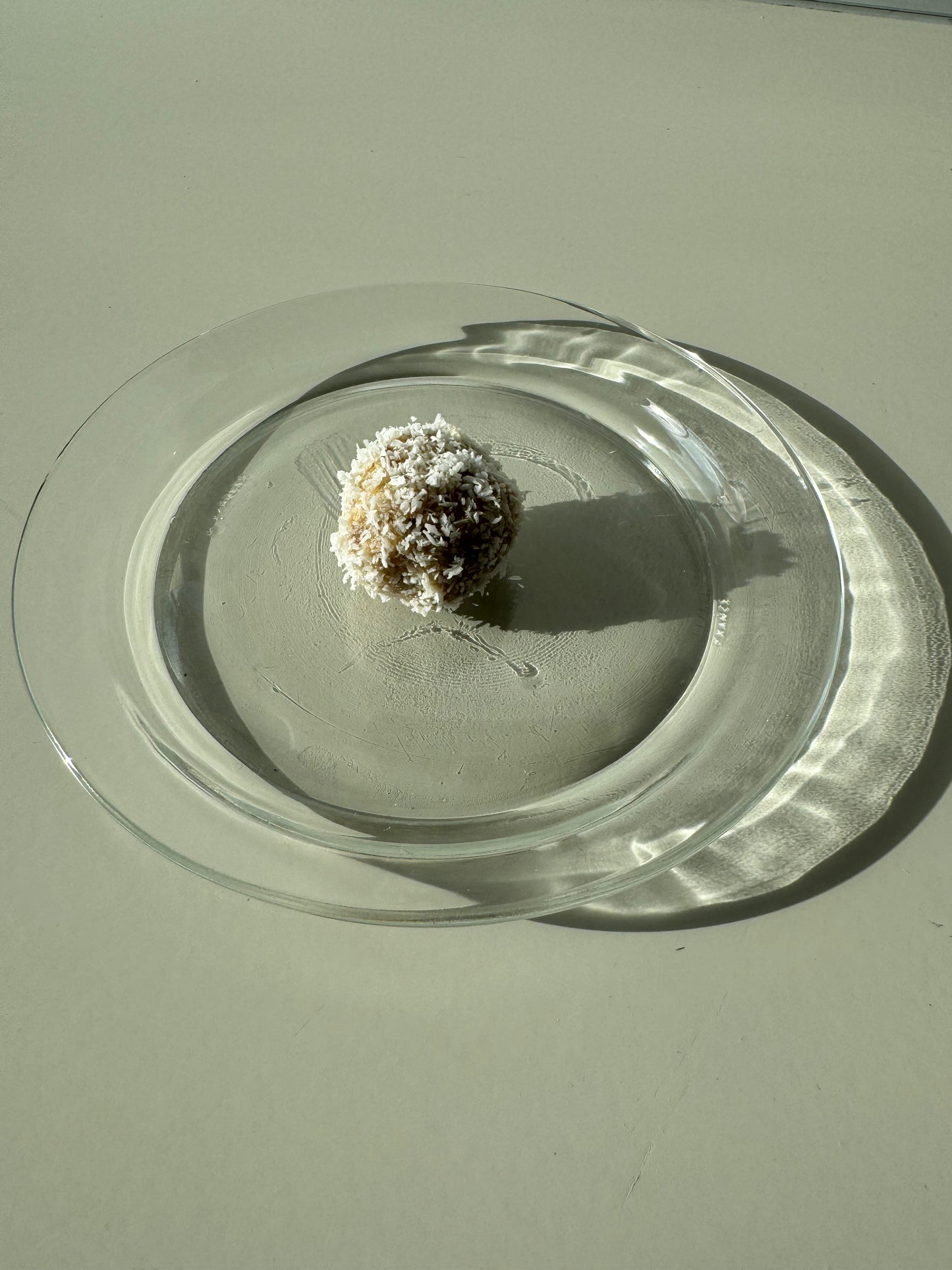 A plate of round bliss ball made of oats, almonds, dates, and coconut, sprinkled with cinnamon and coconut flakes.