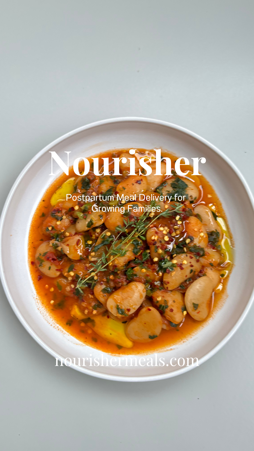 A bowl of creamy tomato butter beans with fresh kale, served on a white plate.