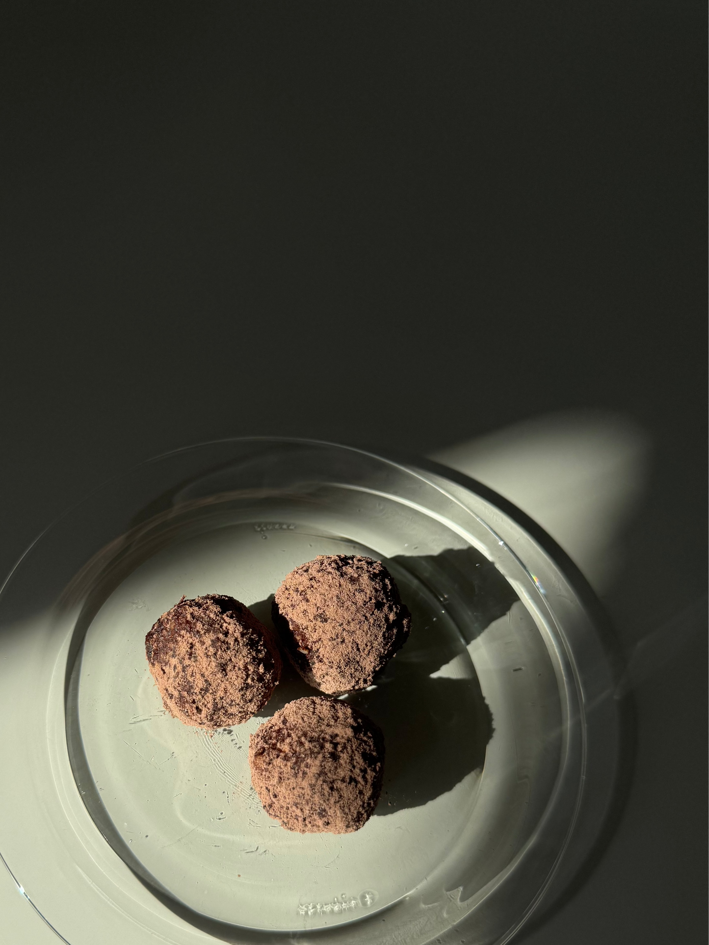 Three brown spherical objects on a white plate with a dark background