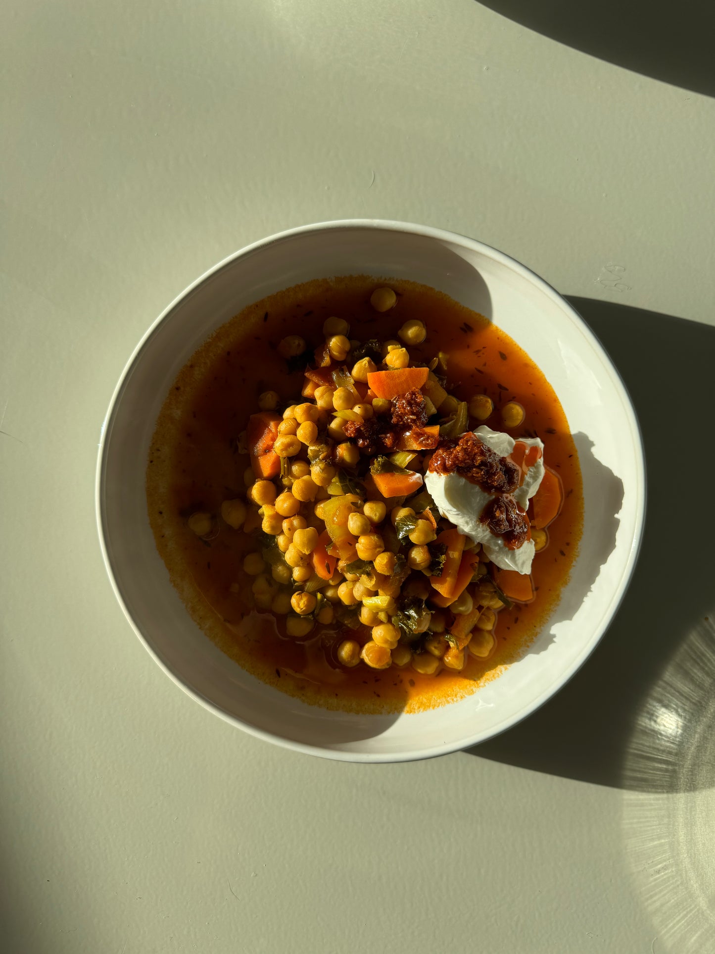 A bowl of chickpea stew with fresh carrots, lacinato kale, onions, and garlic, simmered in a rich tomato base with vegetable broth.