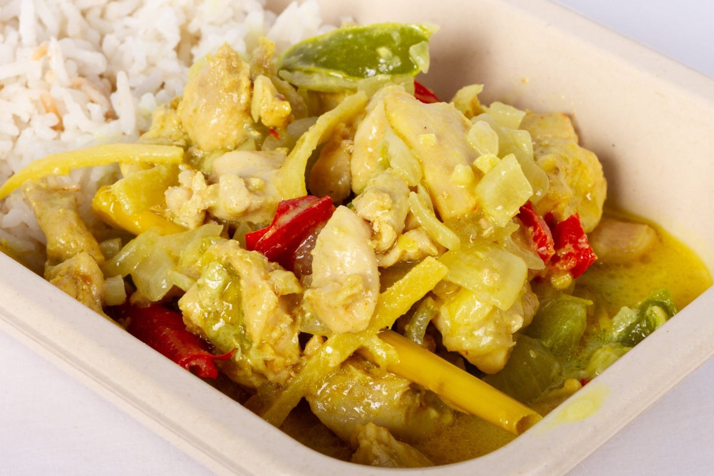 Two bowls of Creamy Lemongrass Coconut Chicken, garnished with herbs and spices, served on a white plate.