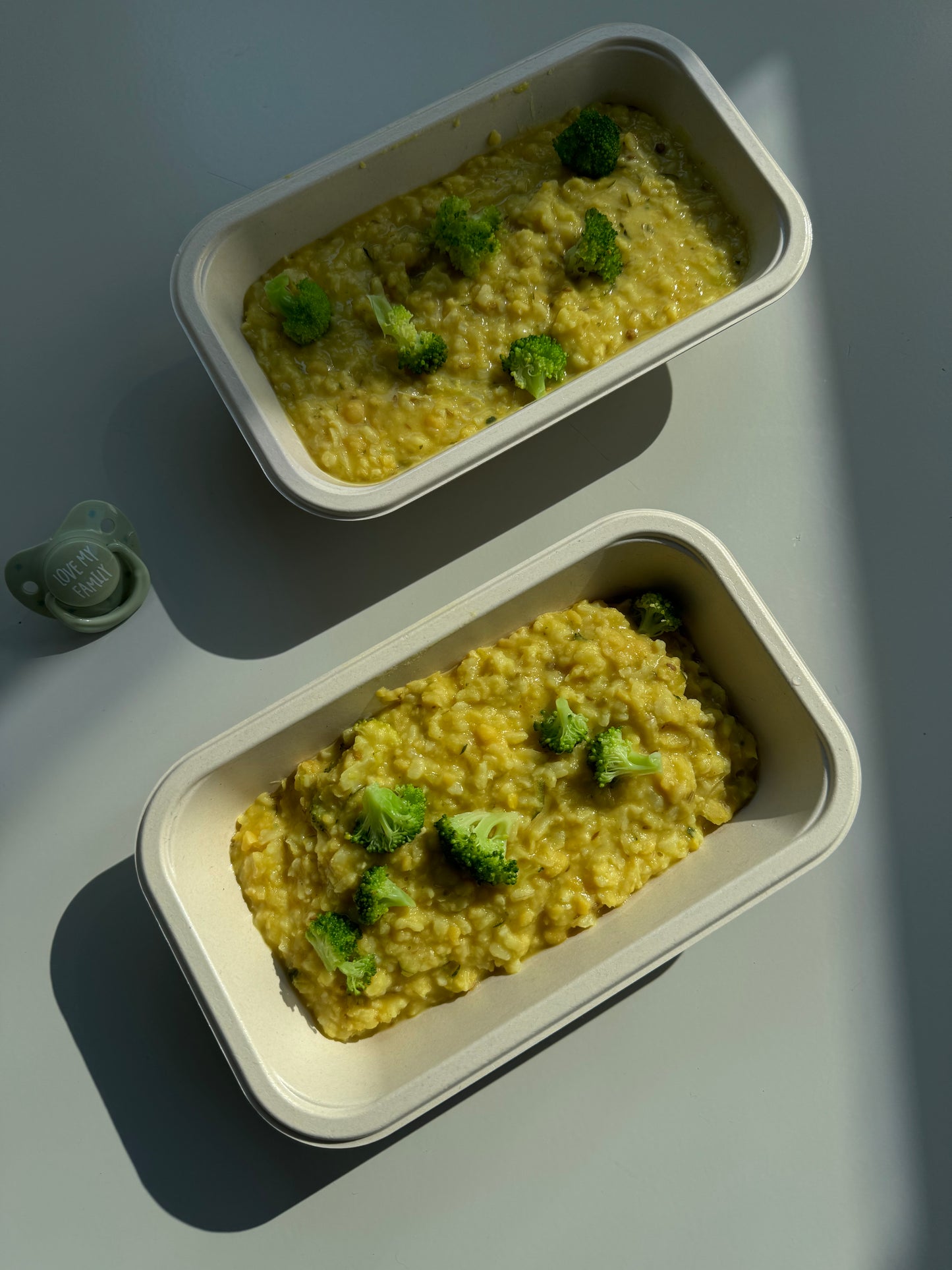 Kitchari packed in two containers with a pacifier in the shade