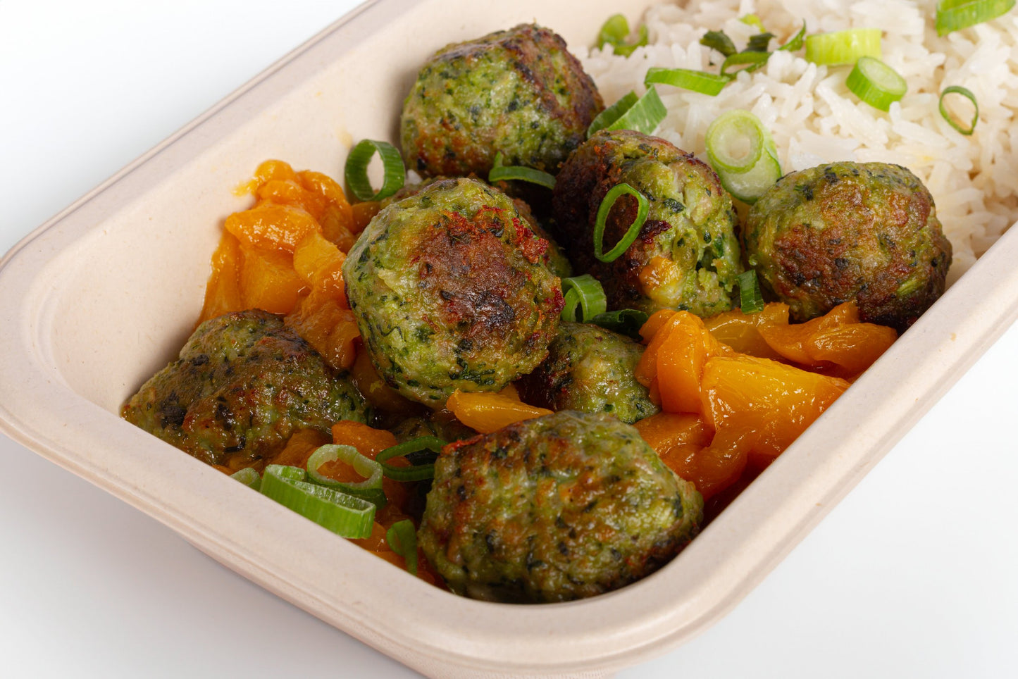A bowl of ginger chicken meatballs in pear sauce, garnished with basil leaves.