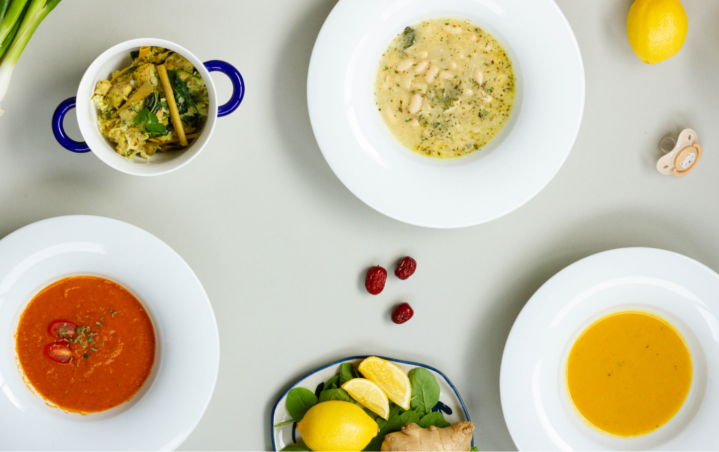 Assorted soups on white plates with garnishes on a light gray background