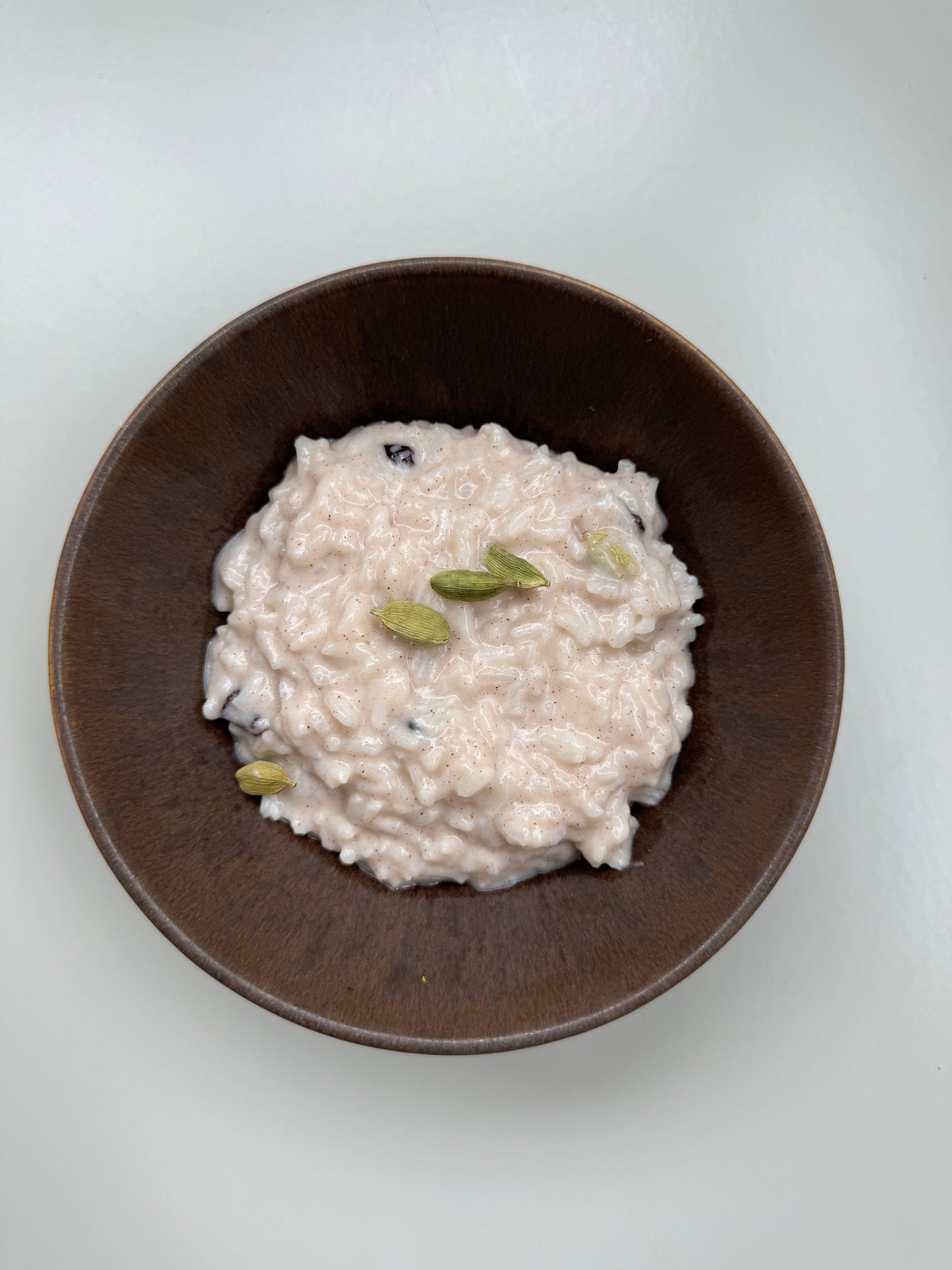 A bowl of Shatavari Rice Pudding on a light background with a shadow cast over part of the image.
