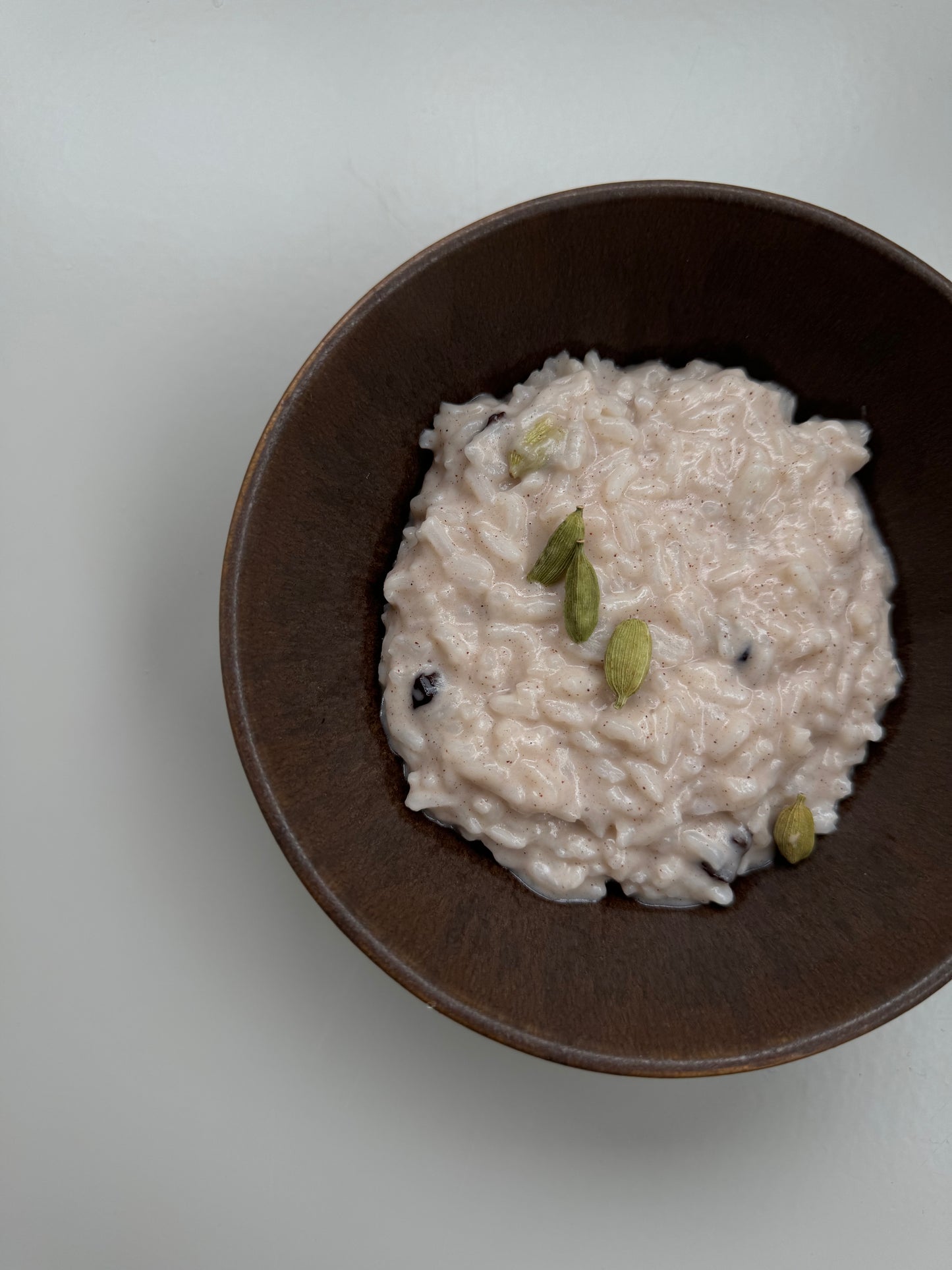 A bowl of Shatavari Rice Pudding on a light background with a shadow cast over part of the image.