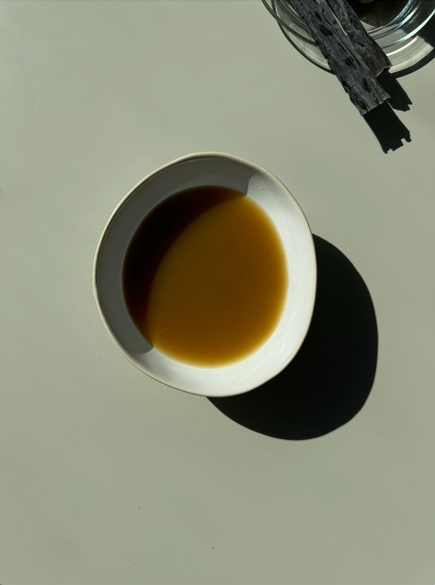 A bowl of Shiitake Immune Boost broth with visible leeks, a lemon wedge, and other ingredients in the background.