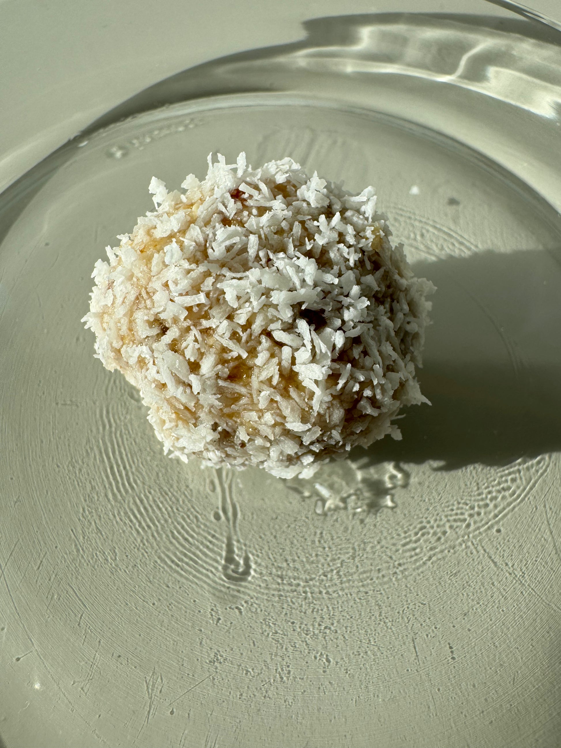 A plate of round bliss ball made of oats, almonds, dates, and coconut, sprinkled with cinnamon and coconut flakes.