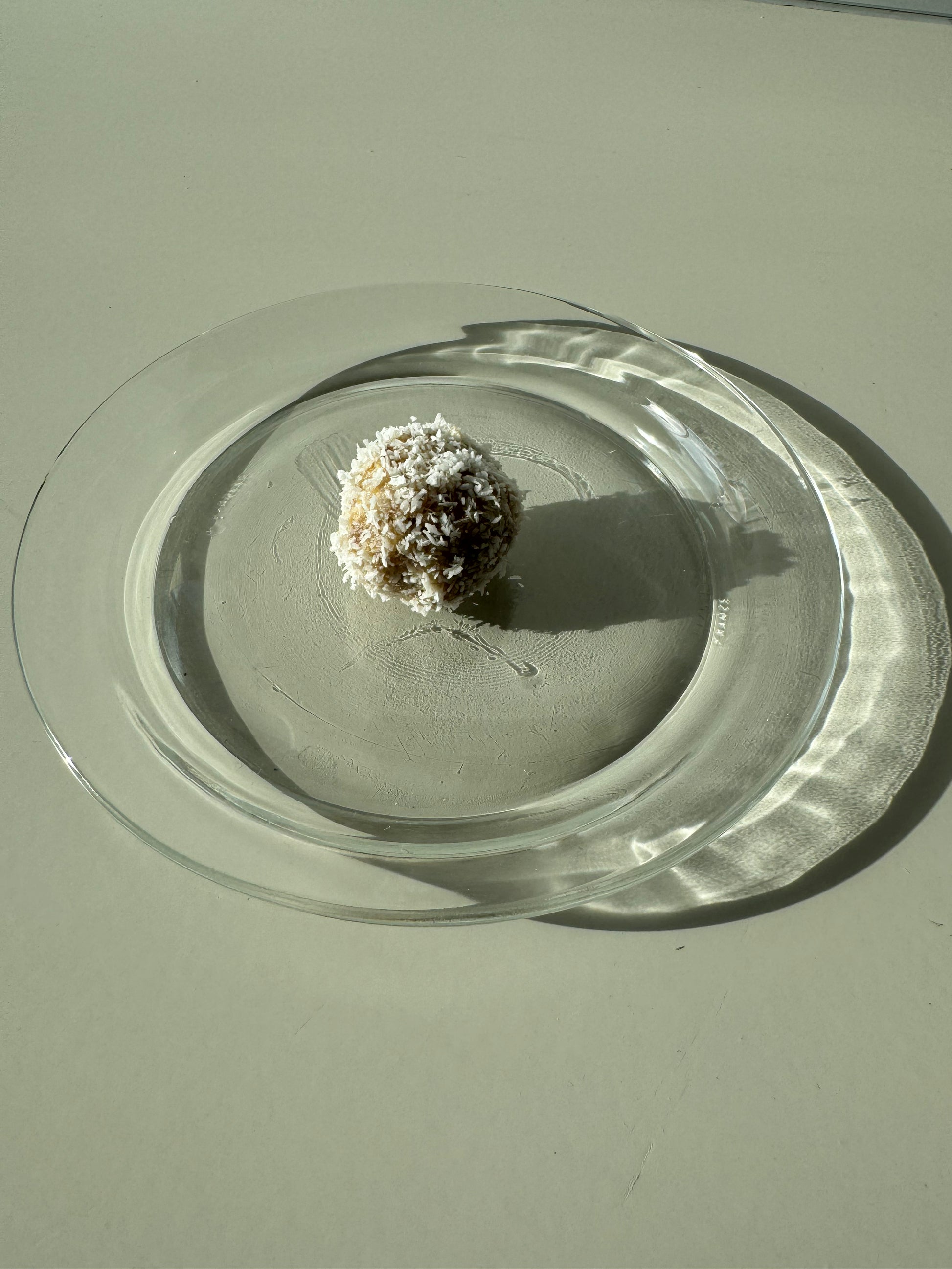 A plate of round bliss ball made of oats, almonds, dates, and coconut, sprinkled with cinnamon and coconut flakes.