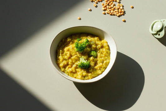 A bowl of Kitchari, a traditional Ayurvedic dish, garnished with herbs, with visible ingredients like lentils and rice.