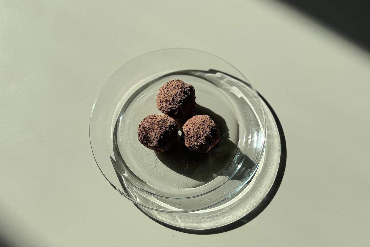Three chocolate truffles on a clear glass plate with a light background