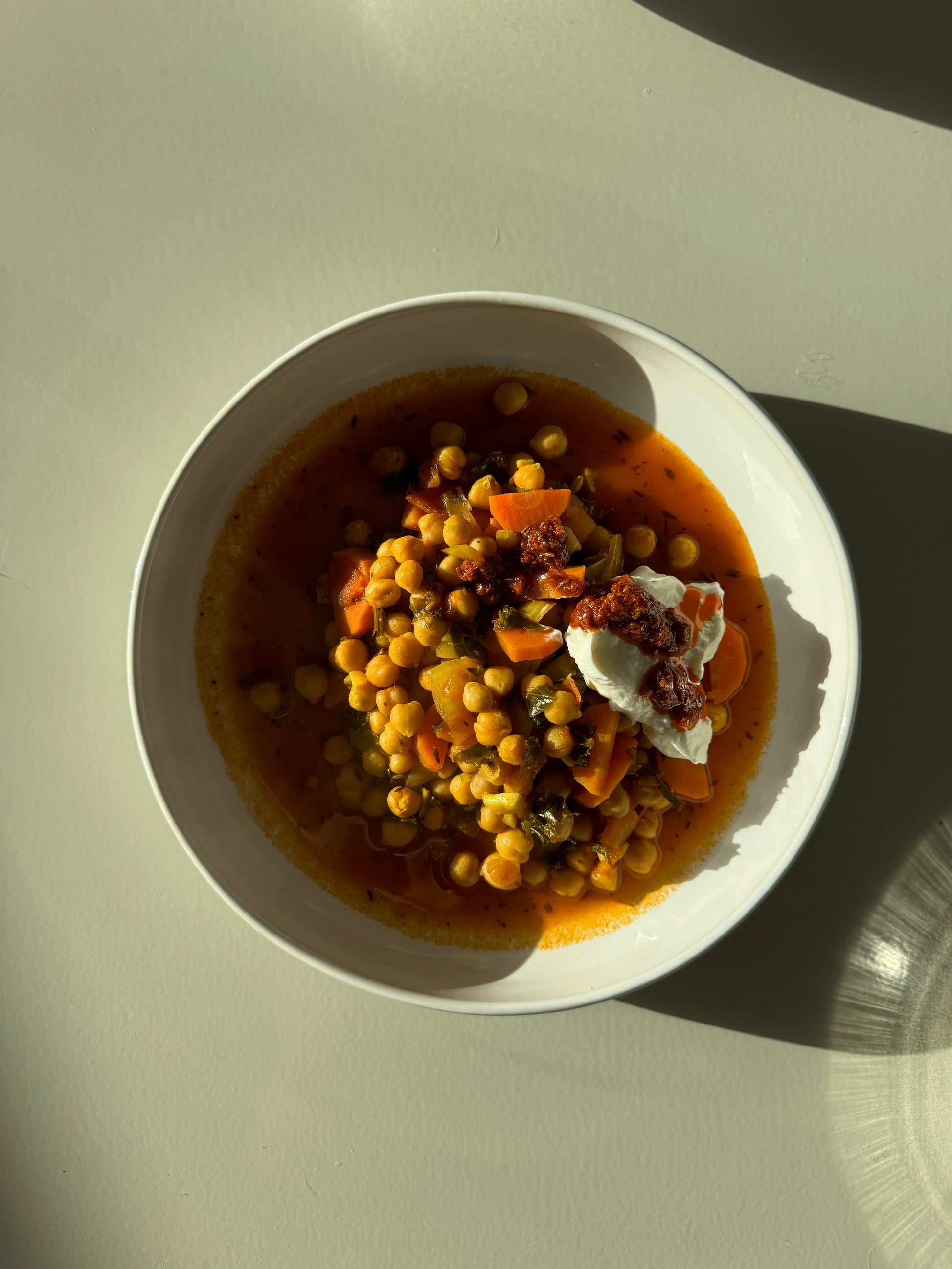 A bowl of chickpea stew with fresh carrots, lacinato kale, onions, and garlic, simmered in a rich tomato base with vegetable broth.