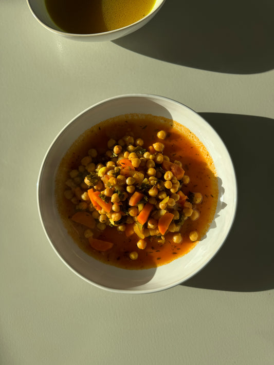 A bowl of chickpea stew with fresh carrots, lacinato kale, onions, and garlic, simmered in a rich tomato base with vegetable broth.