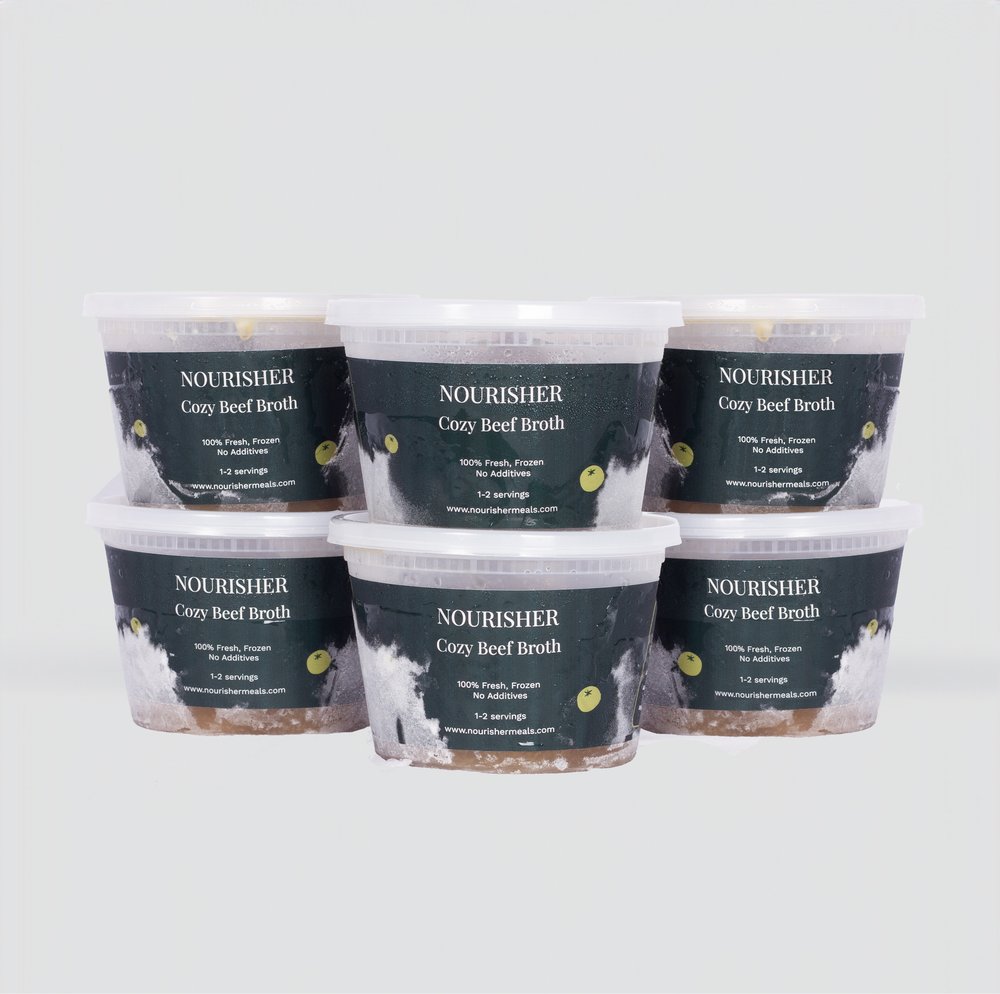 6 packaged units of clear beef broth placed on a table with studio lighting.