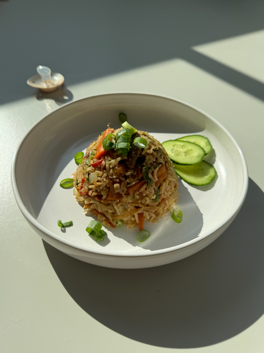 Ginger fried rice with green vegetables and a pacifier in the back. Shadows on plate