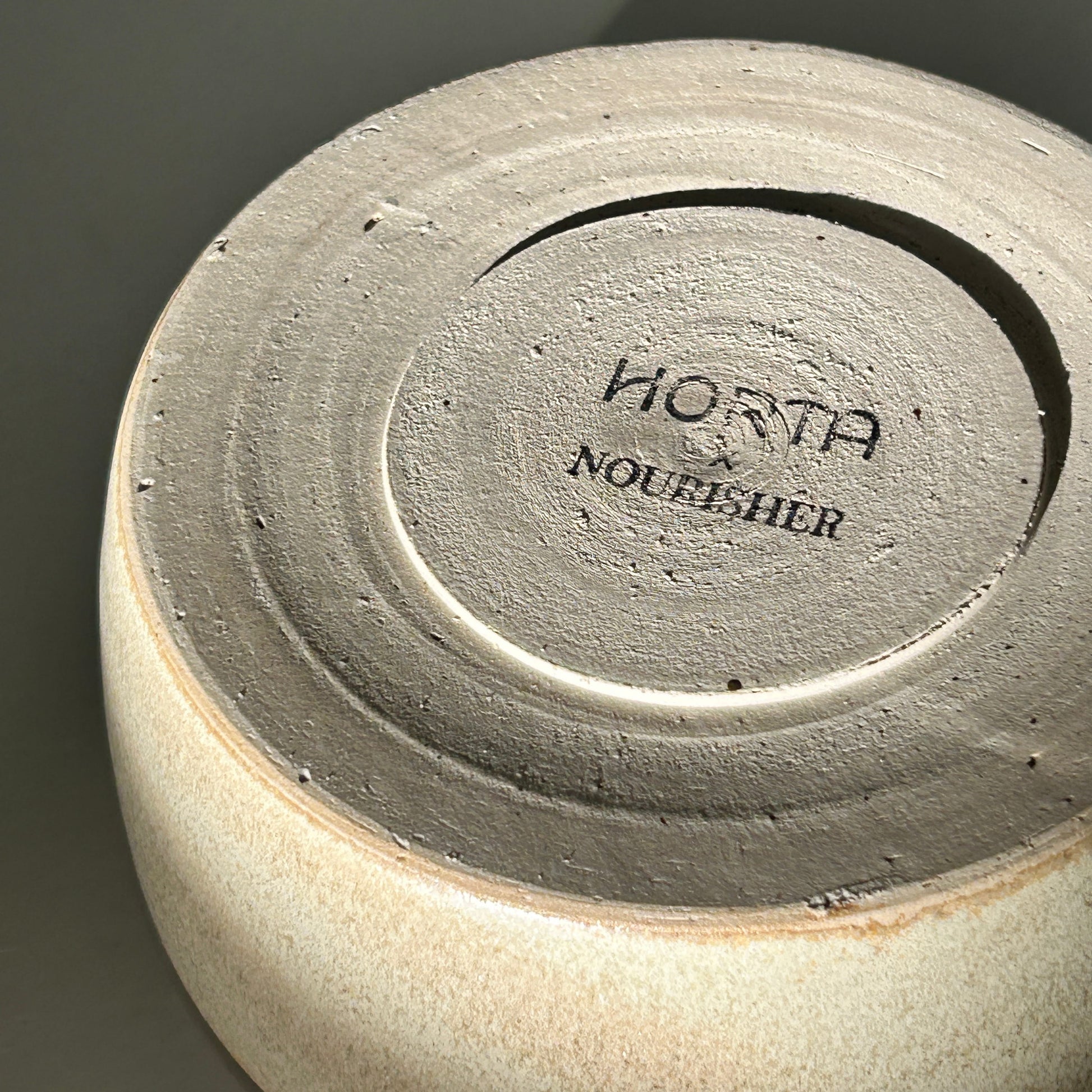 Close-up of a ceramic product with 'Horta Nourisher' branding on a dark background