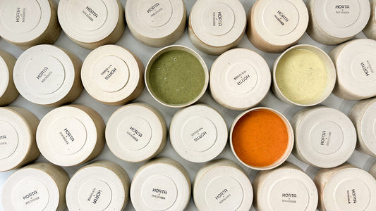 Multiple small containers with visible labels Nourisher Horta on a gray surface