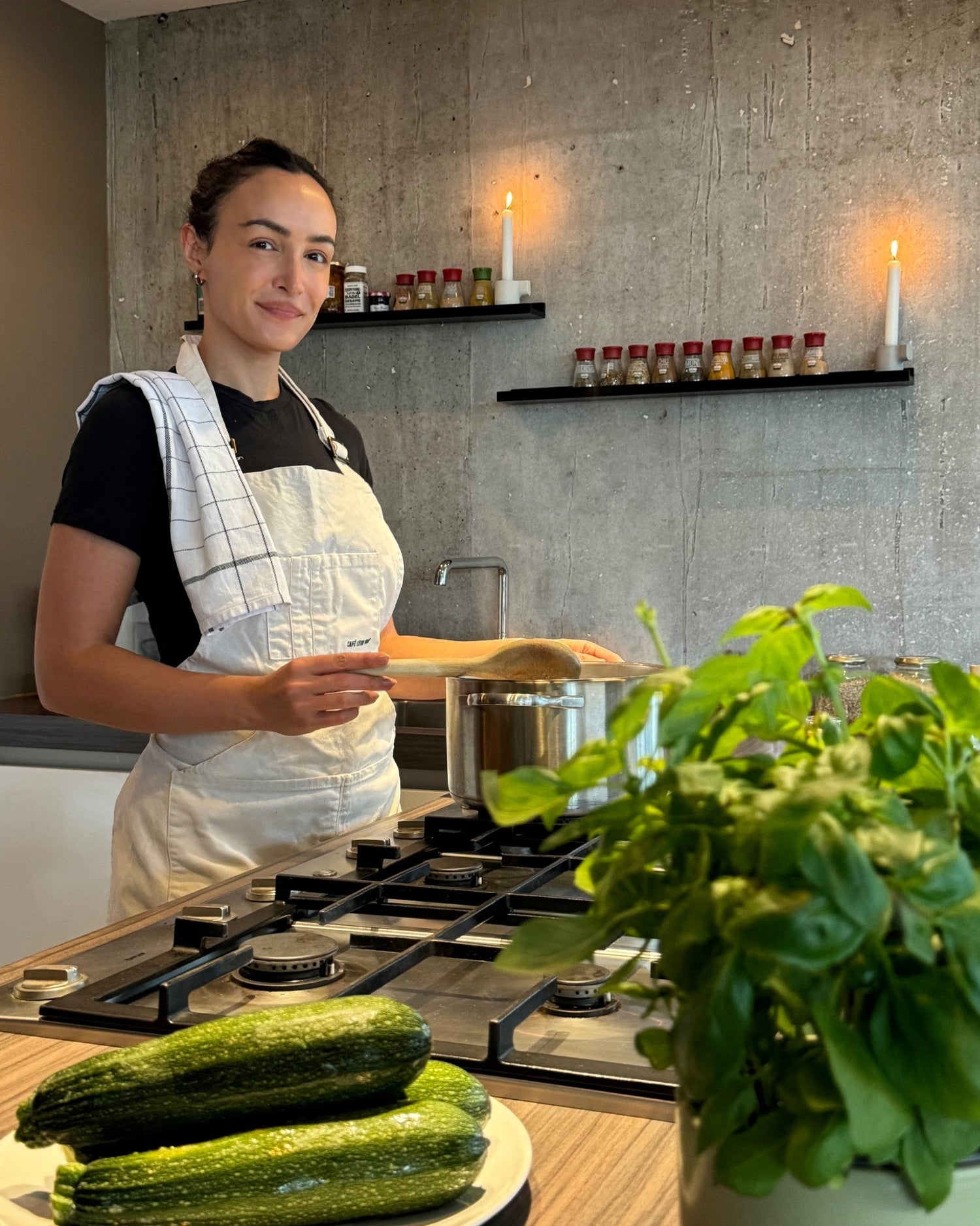 Melli, owner of Nourisher Meals standing in the kitchen with vegetables in the front