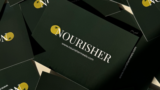 A pile of dark green gift cards with the word 'NOURISHER' printed in white, arranged in a casual pattern.