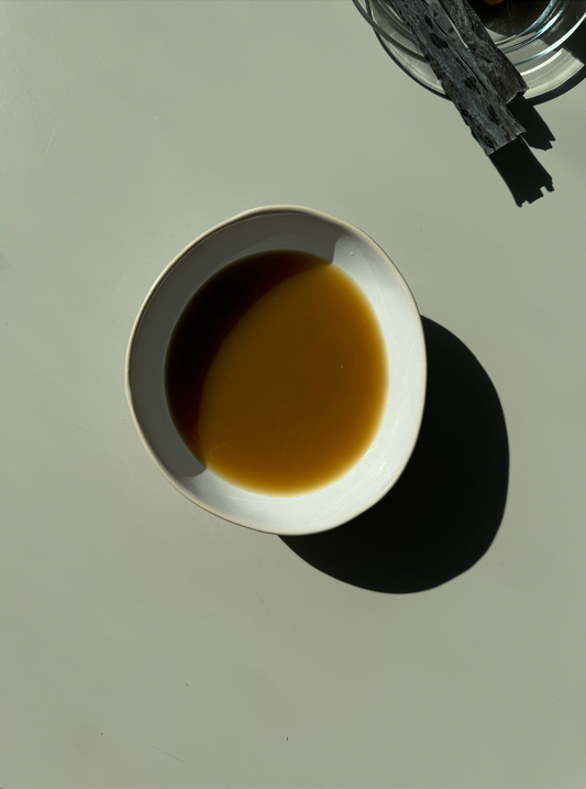 A bowl of Shiitake Immune Boost broth with visible leeks, a lemon wedge, and other ingredients in the background.