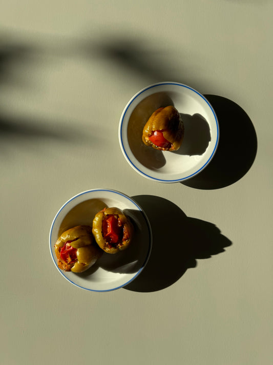 two bowls of stuffed peppers, one in one dish, two in the other with shadows