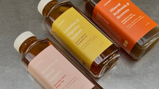 Three clear plastic bottles of liquid supplements with white caps, arranged diagonally on a textured gray surface. The bottles contain amber-brown liquid and feature labels in pink, yellow, and orange with white text.
